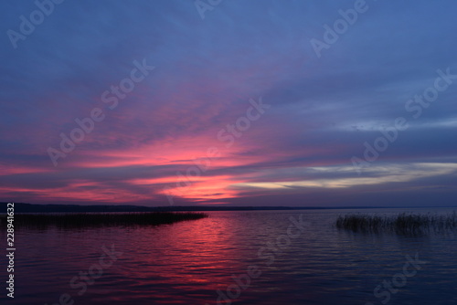 Twilight sky in bright colors sunset glowing above water surface the lake