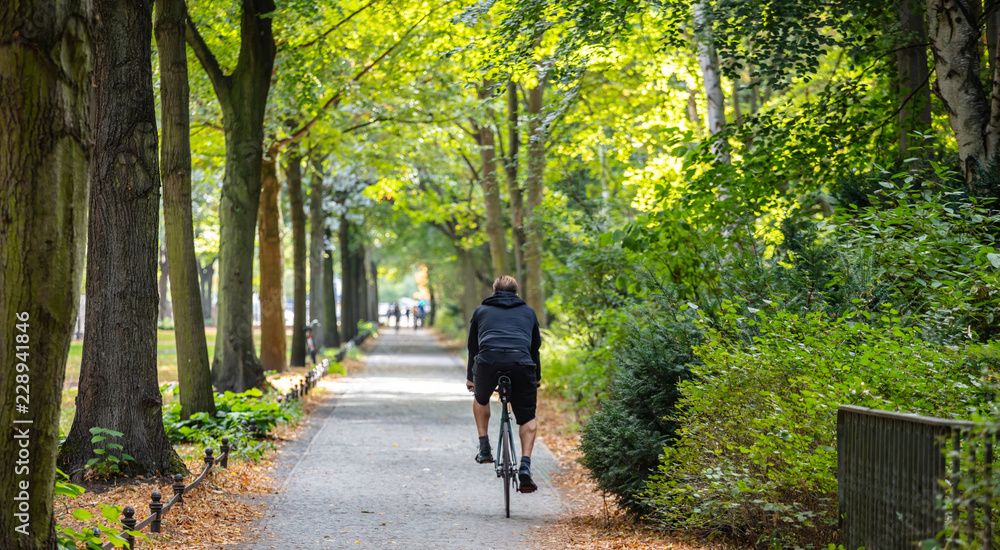 Tiergarten city park in Berlin, Germany. View of a young man riding a bike