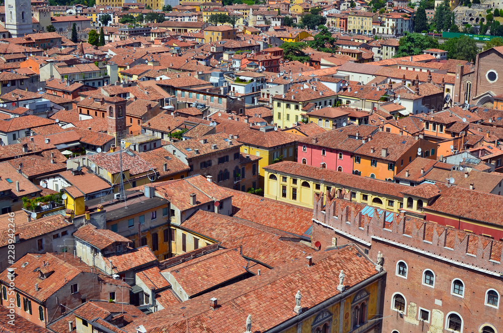 On the red tiled roofs of a small no name  Italian city there are many satellite  TV antennas and roof windows