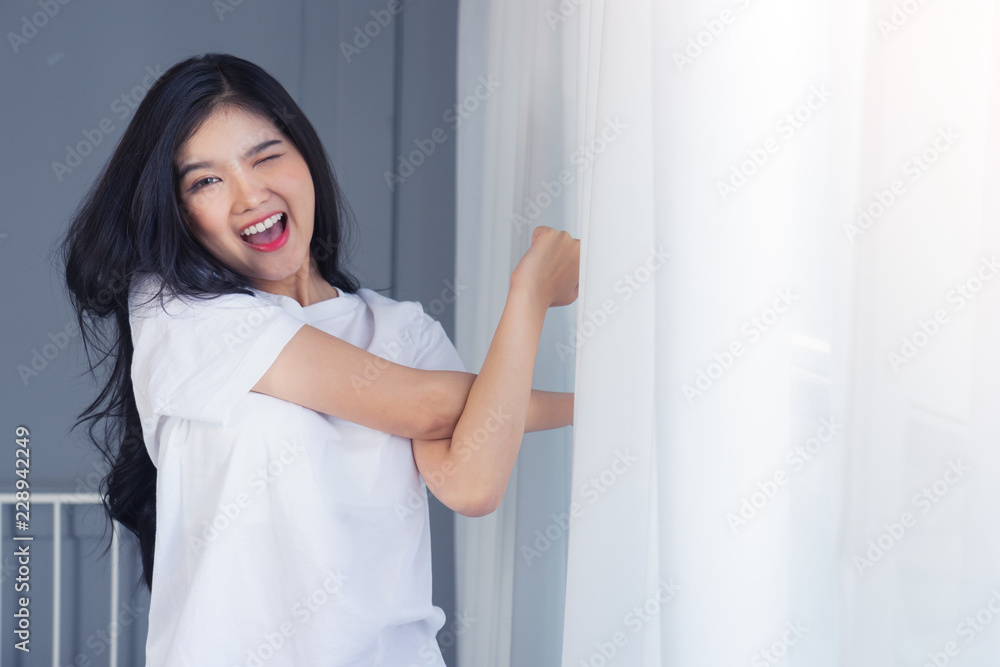 Woman stretching in bed after waking up, back view. Woman sitting near the big white window while stretching .she happy and smile. Woman stretching in bed after waking up, back view. Woman sitting near the big white window while stretching .she happy and smile.