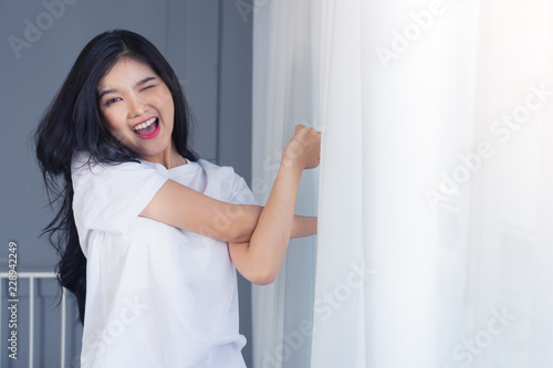 Woman stretching in bed after waking up, back view. Woman sitting near the big white window while stretching .she happy and smile.