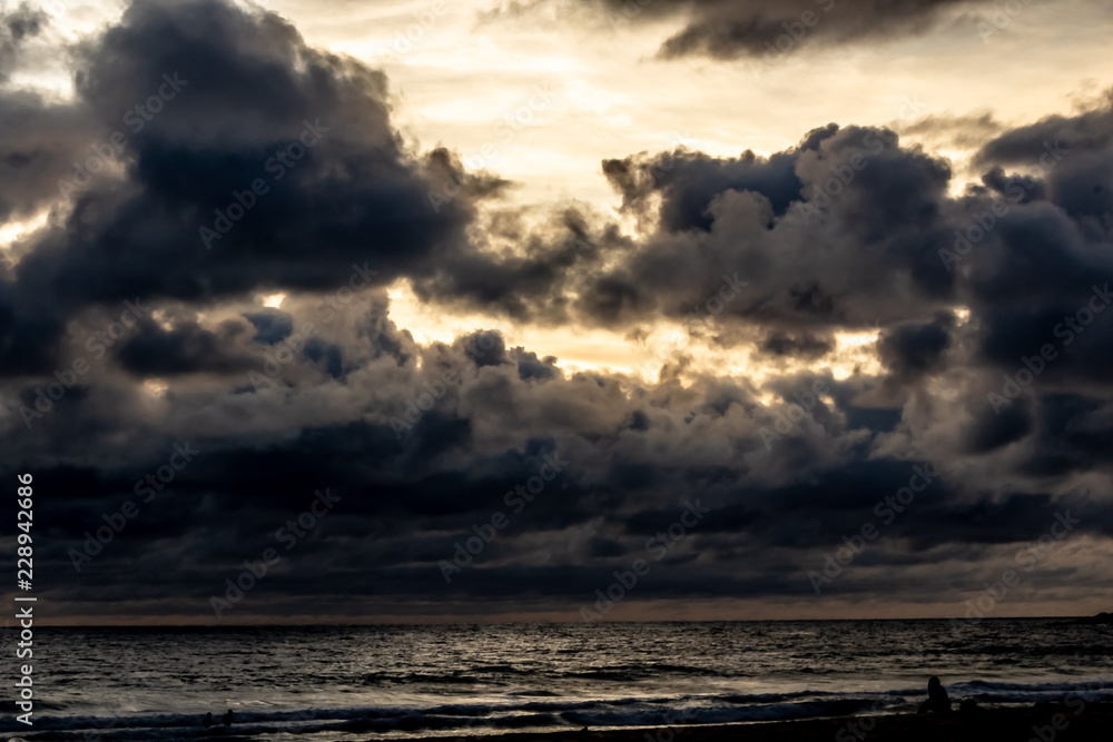 Dramatic clouds over the ocean as the sun sets and the sky turns dark, Karon Beach, Phuket Thailand.