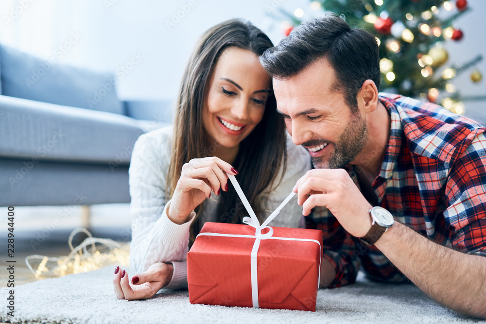 Happy couple opening a Christmas present Happy couple opening a Christmas present