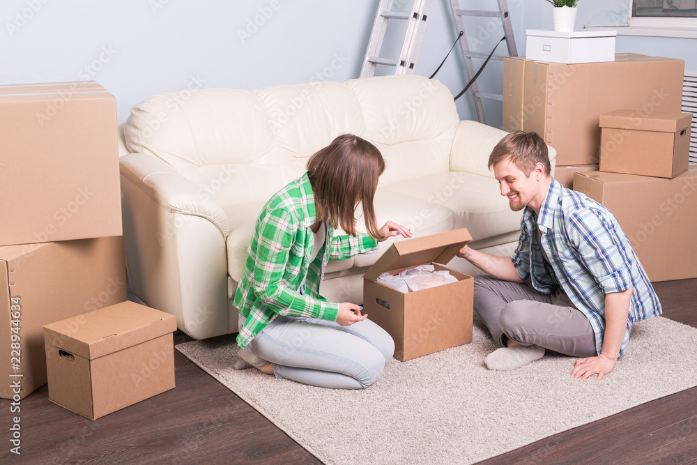 Moving and real estate concept - happy couple having fun unpacking cardboard boxes at new home Moving and real estate concept - happy couple having fun unpacking cardboard boxes at new home