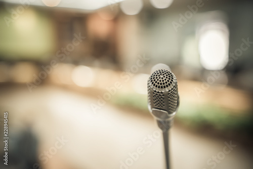 Front Microphone on abstract conference hall prepare for speaker on stage in seminar room, Business meeting and education in teaching classroom or Event light convention hall Background. photo