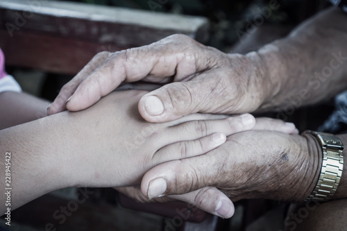 Hands holding together takecare of Asian elderly or grandfather hands wrinkled skin touching teenage with feeling take care of Love. Relationship of Family father day concept
