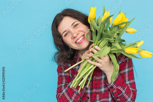 Laughing young caucasian woman with bouquet of tulips on blue background. photo