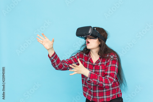 Future, technology and people concept - Surprised young woman wearing vr-glasses on blue background