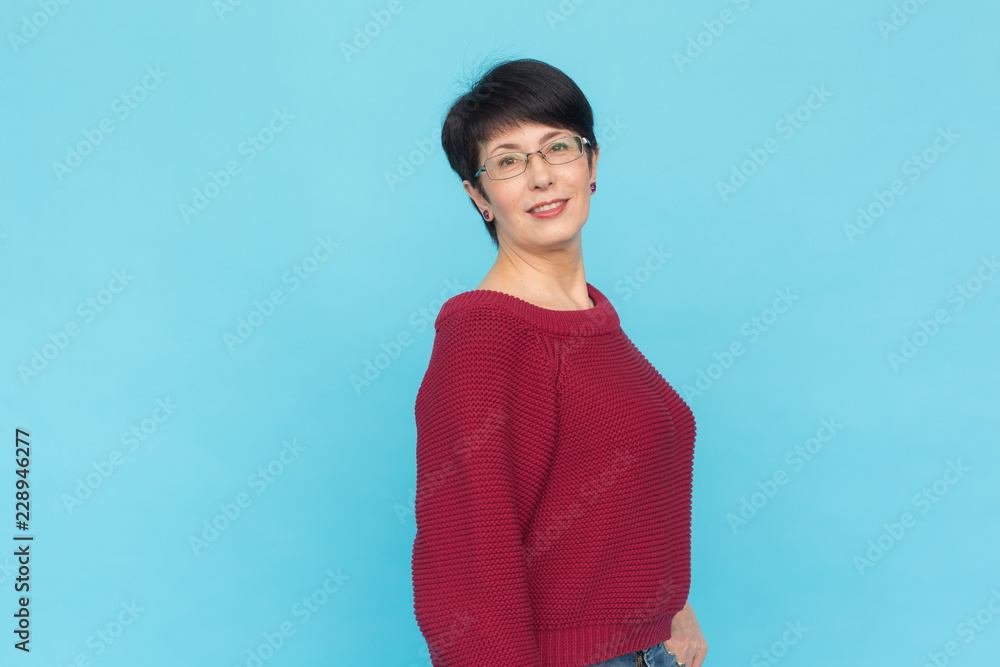Fashion, style and people concept - smiling pretty middle-aged woman on turquoise background with copy space Fashion, style and people concept - smiling pretty middle-aged woman on turquoise background with copy space
