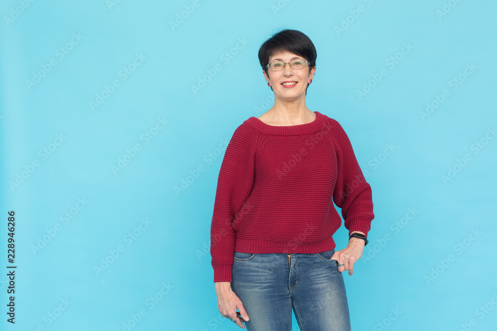 Fashion, style and people concept - smiling pretty middle-aged woman on turquoise background with copy space Fashion, style and people concept - smiling pretty middle-aged woman on turquoise background with copy space