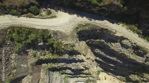 Aerial rise with camera tilt revealing old limestone quarry pit and surroundings on bright sunny day photo