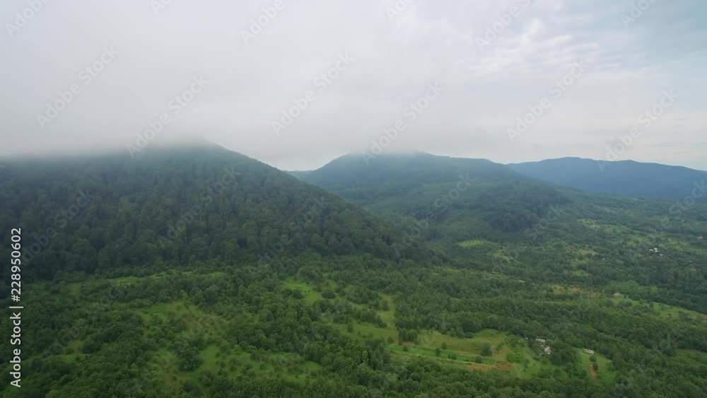 The flight above the mountains is covered with fog. Fairy green trees and gardens. The flight above the mountains is covered with fog. Fairy green trees and gardens.