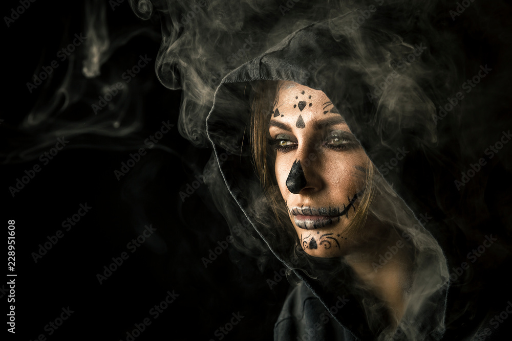 Stylish woman with halloween make up posing isolated on black background with the smoke around her and beautiful studio light.