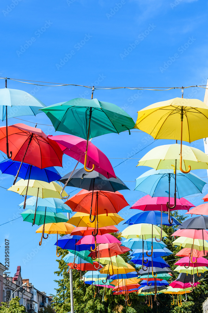 Different colorful umbrellas hanging over the street against sky