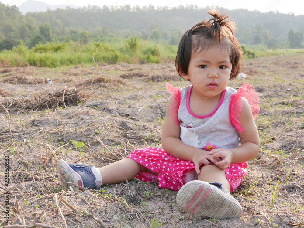 Little Asian baby girl, 18 months old, sitting on outdoor ground Little Asian baby girl, 18 months old, sitting on outdoor ground