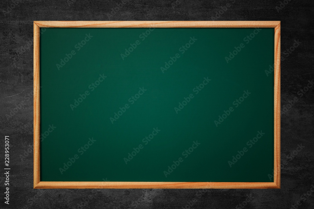 Empty green chalkboard or school board background and texture with wood frame on the black wall, education and back to school concept. Empty green chalkboard or school board background and texture with wood frame on the black wall, education and back to school concept.