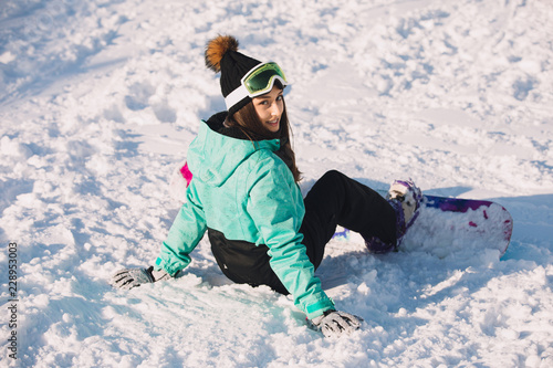 Leisure, sport concept - woman snowboarder sitting on snow