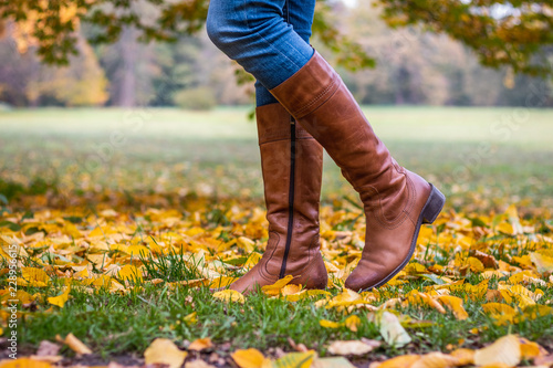 Obraz na plátně Woman wearing brown leather boot and walking in fallen leaves