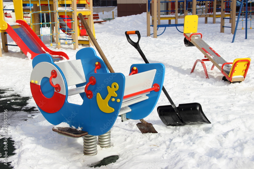Kids swing and snow removal equipment on modern new beautiful Playground in Mytischi in Moscow area in winter snowy day - children leisure on the outdoor