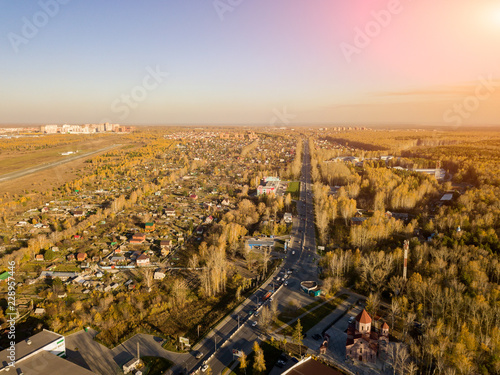 Landscape on the outskirts of the city with a view of the trees and a forest with a large motorway in the middle of a blue sky without clouds on a warm autumn day. Indian summer.