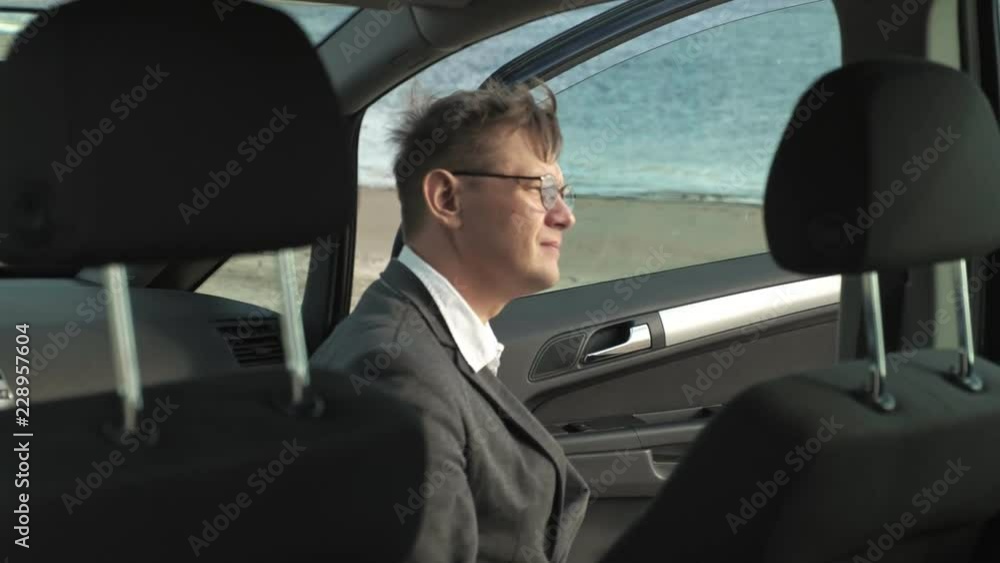 Businessman with a laptop suitcase working relaxing on the beach near his car. Businessman with a laptop suitcase working relaxing on the beach near his car.