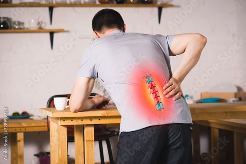Tableau sur toile Pain in the spine, a man with backache at home, injury in the lower back