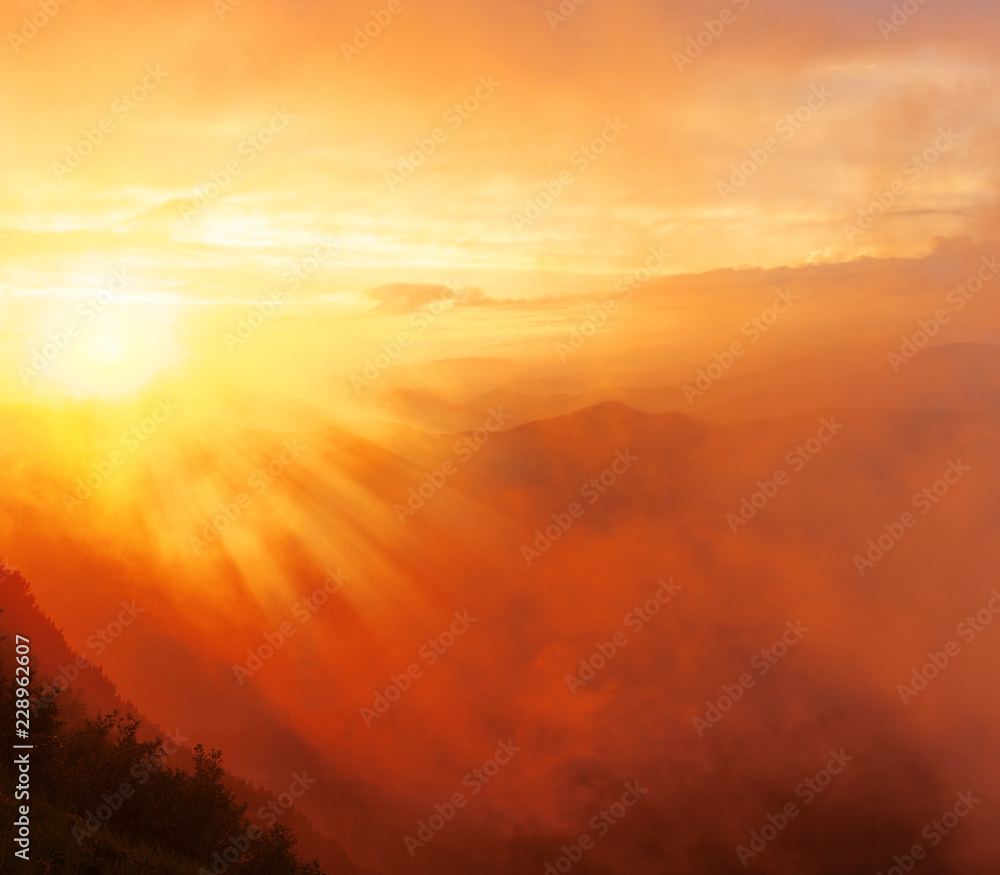 Landscape - sunset with mountain view, orange bright fog illuminated of sunlight with clouds in the sky