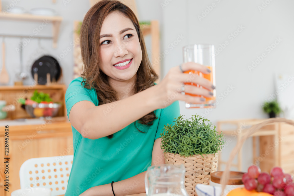 young woman and smiling with juice on hand in the kitchen young woman and smiling with juice on hand in the kitchen