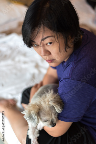 Asian woman hugging dog so cute on bed in bedroom