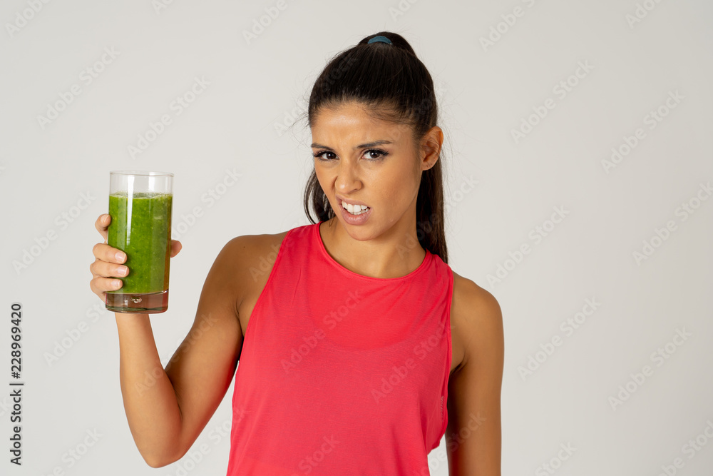 Beautiful young sport woman tired of diet holding green smoothie in dislike Beautiful young sport woman tired of diet holding green smoothie in dislike