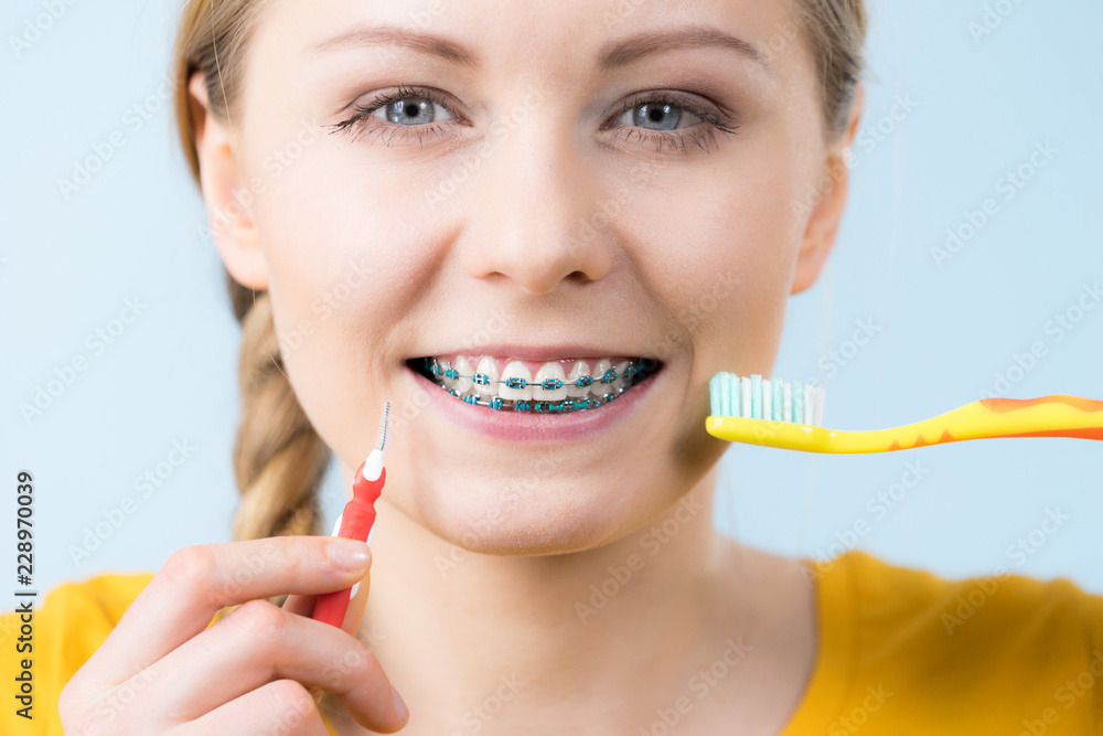 Woman smiling cleaning teeth with braces Woman smiling cleaning teeth with braces