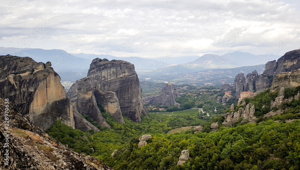 The Rousanou Monastery and The Monastery of St. Nicholas Anapausas in the background - valley famous for Greek monasteries surrounded by dark cliffs, Meteora, Kastraki, Kalambaka, Greece