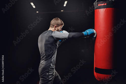 Male boxing in punching bag. Training man in gym. © Parilov