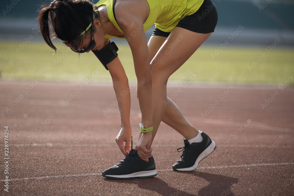 Sportswoman tying shoelace before run on stadium
