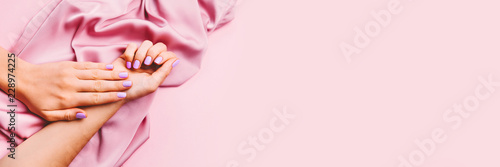 Fotografia Beautiful woman manicure on creative pink background with silk fabric