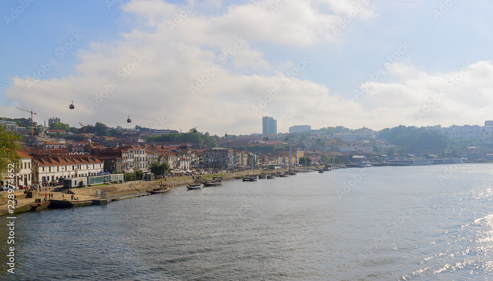 Scenic view of Vila Nova de Gaia from Dom Luis I Bridge in a sunlight. Porto, Portugal. The boats on the waterfront of the river Douro. Scenic view of Vila Nova de Gaia from Dom Luis I Bridge in a sunlight. Porto, Portugal. The boats on the waterfront of the river Douro.