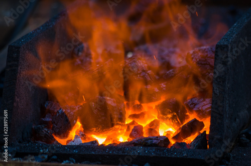 blacksmith furnace with burning coals, tools, and glowing hot metal workpieces