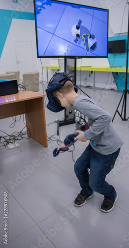 Little boy in vr headset playing virtual reality game with controllers