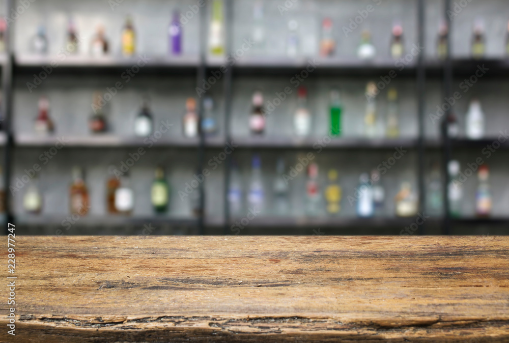 Empty wooden table and interior bar counter with defocused  bottles of restaurant background