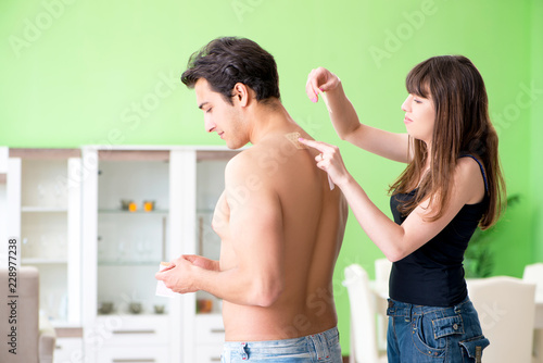 Wife applying pepper Capsicum plaster to husband to relieve pain