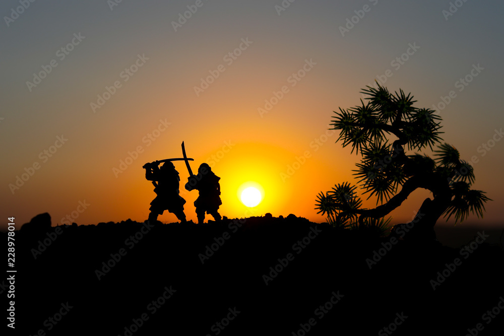 Silhouette of two samurais in duel. Picture with two samurais and sunset sky. Selective focus