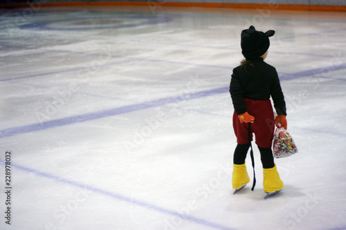 costumed child on ice skates with pack of candy