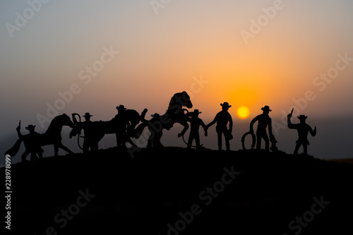 Cowboy concept. Silhouette of Cowboys at sunset time. A cowboy silhouette on a mountain with an yellow sky.