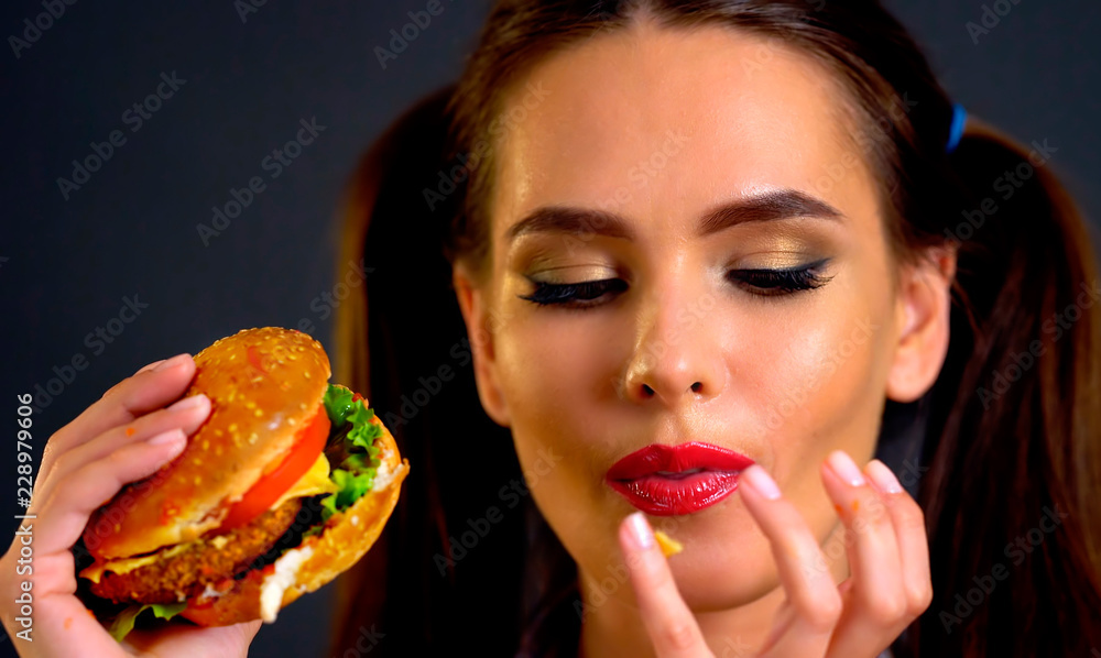 Woman bite big hamburger. Girl eat fast food and lick your fingers after eating. Woman bite big hamburger. Girl eat fast food and lick your fingers after eating.