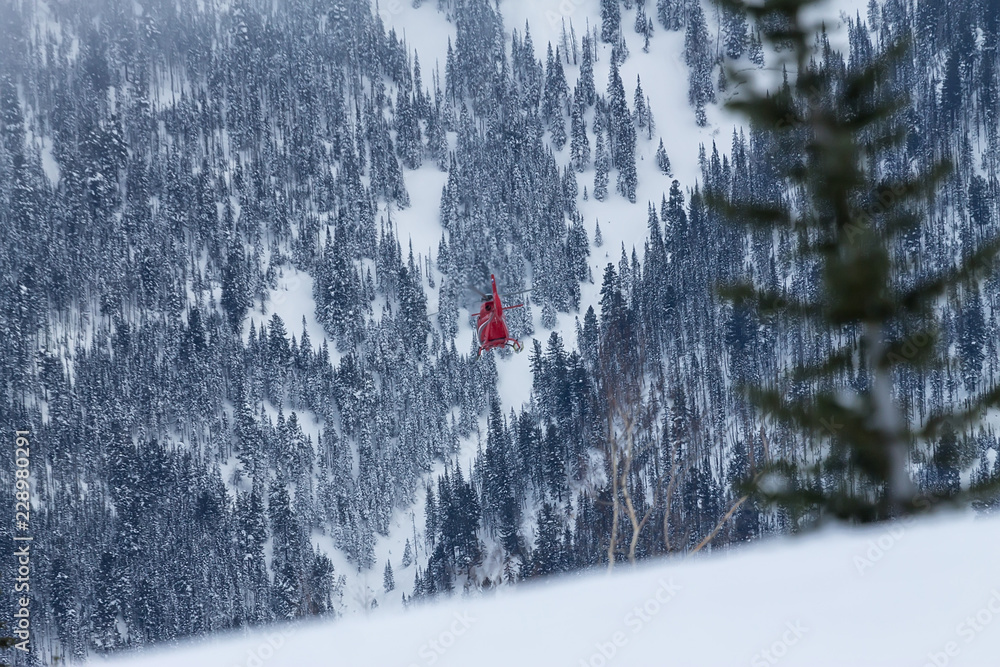 Red rescue helicopter fly in snowy mountains