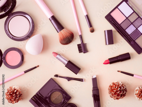 top view of cosmetics concept with lipstick, makeup products, Eyeshadow Palette, powder on cream color table background.