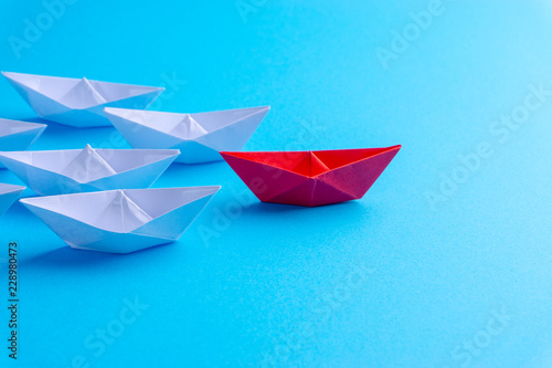 White and red paper ship in one direction on blue background. Business for innovative solution concept with selective focus © instagram.com/_alfil