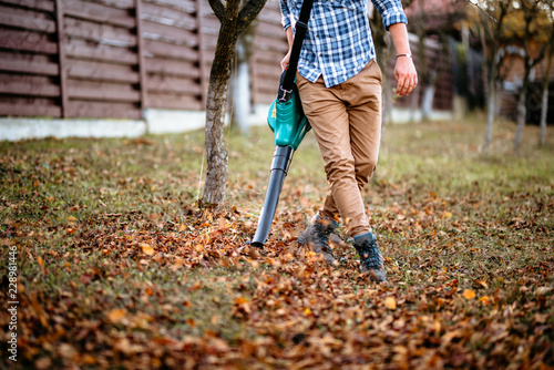 professional gardener using leaf blower and working in the garden