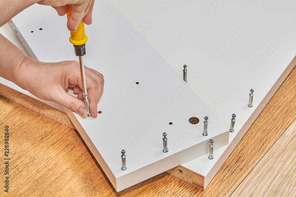 Installer uses cam lock screws as fasteners for flat-pack furniture. foto  de Stock | Adobe Stock