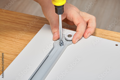 Фотография Joiner is mounting slide bracket for drawer using screwdriver.